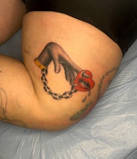 a woman's thigh with a tattoo of a red heart and chain